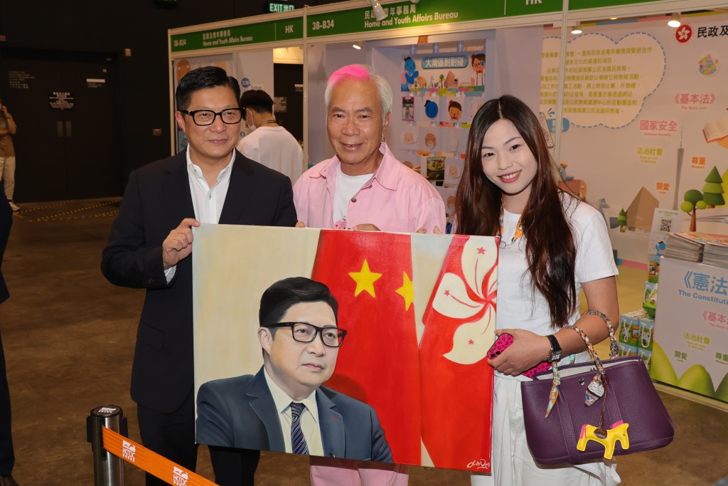 今年7月出席书展分享会时，Chris更亲手送赠肖像油画给保安局局长邓炳强（左）。