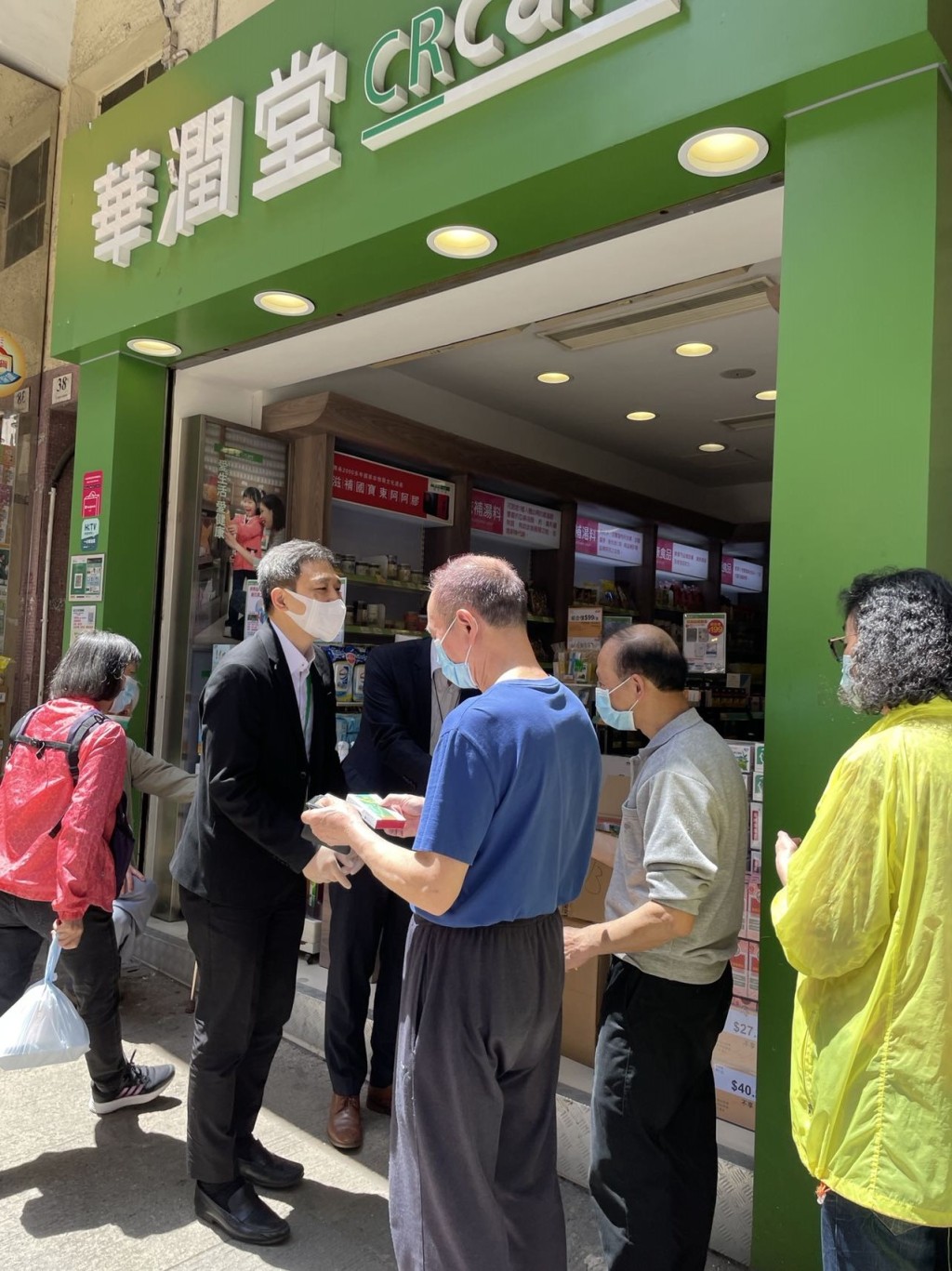 華潤堂總經理曹偉勇(左二)向年滿65歲或以上長者免費派發連花清瘟膠囊。