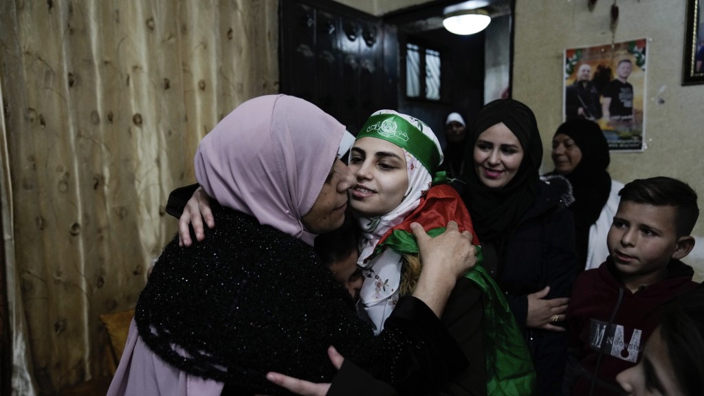 戴着哈馬斯頭帶的獲釋女子回到家裏，與親友擁抱。 美聯社