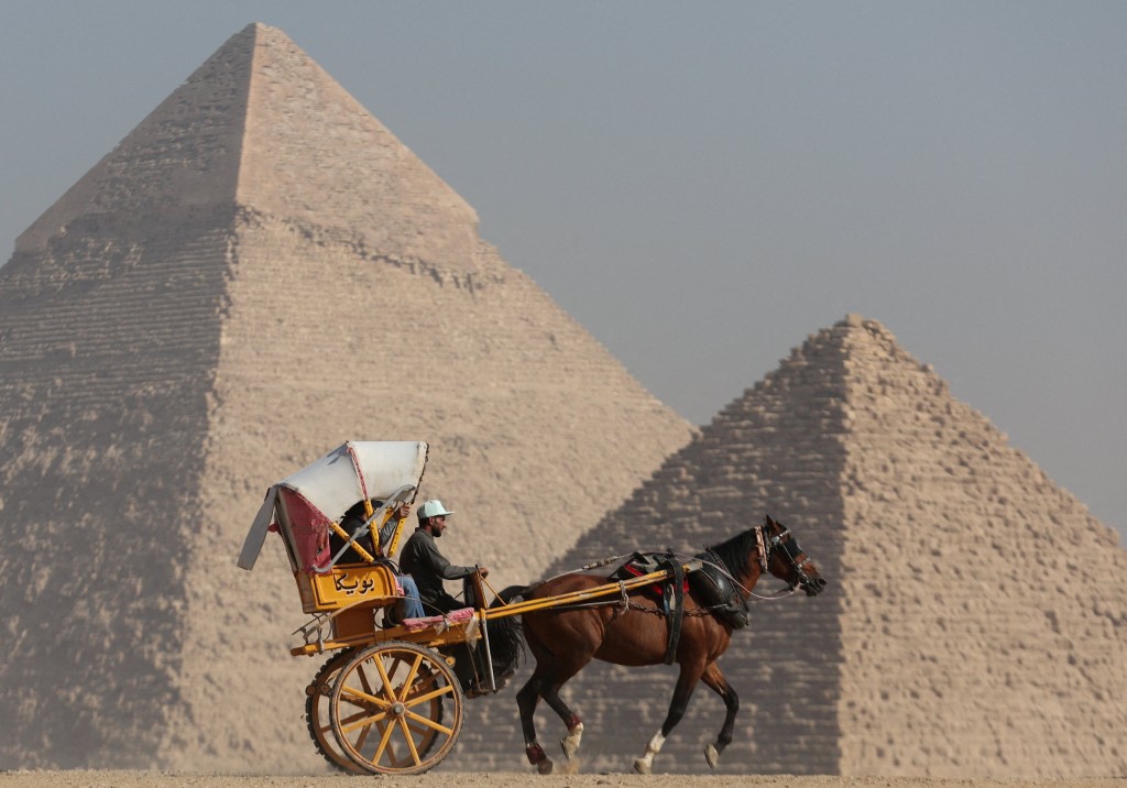 游客在吉萨大金字塔高原前乘坐马车。路透社