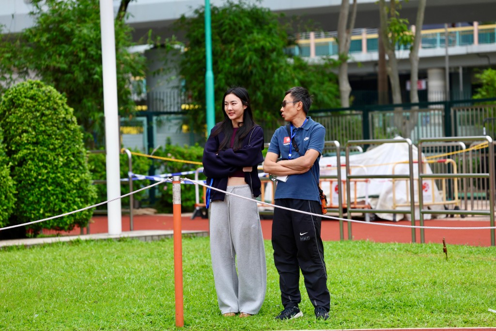 香港女子跳高纪录保持者杨文蔚跟教练温达勇到场看师妹们比赛。徐嘉华摄