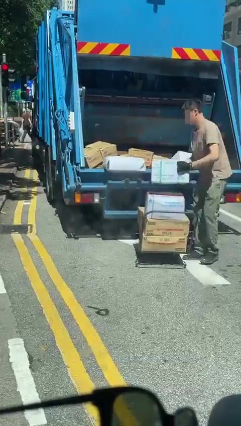 工人在垃圾車前搬紙箱。網上截圖