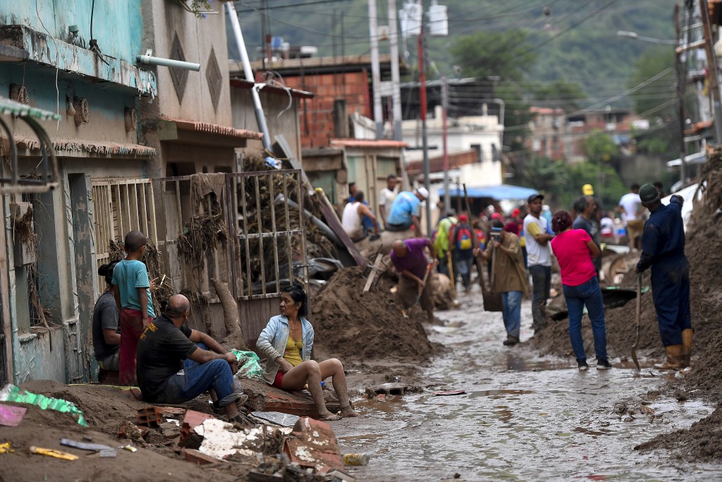 民眾在被洪水淹沒的街道上清理泥土並找回財物。AP