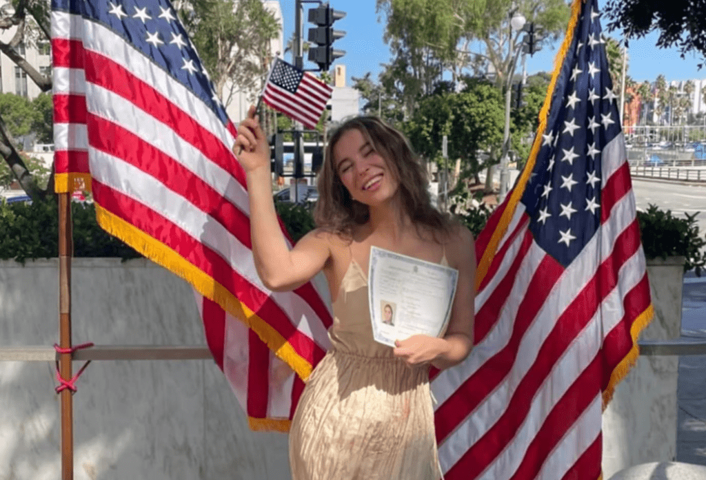卡瓦娜拿著美國入籍文件，面露微笑，手上還舉著美國國旗。Ｘ平台