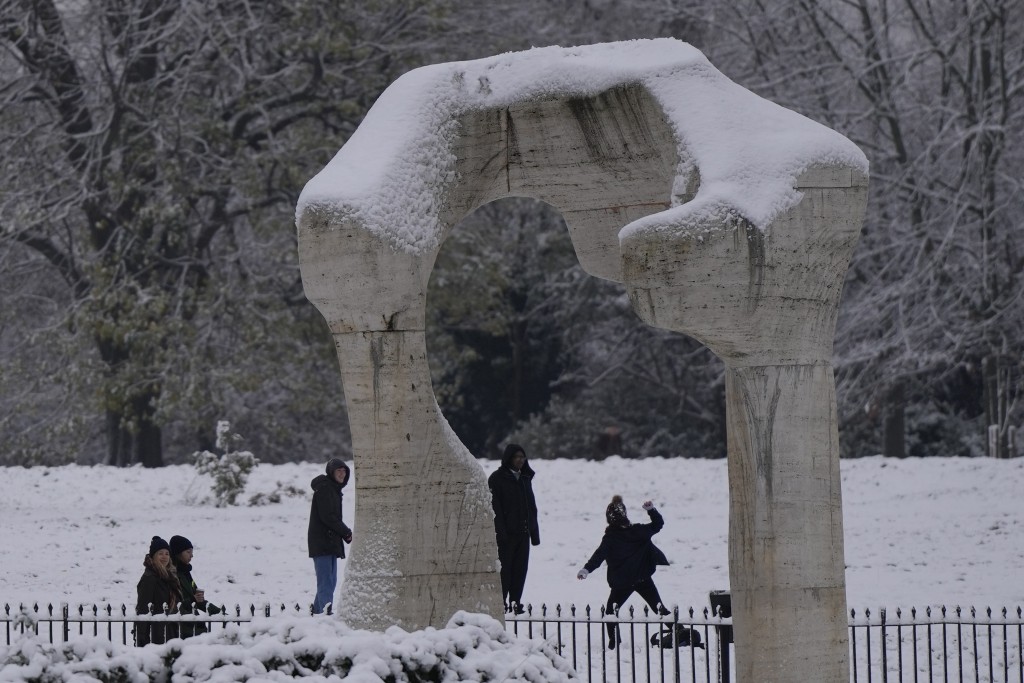 民眾在倫敦肯辛頓花園的英國藝術家亨利·摩爾 (Henry Moore) 「拱門」雕塑旁邊打雪仗。AP