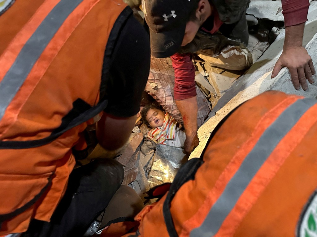 救援人員在瓦礫堆中拉出一名孩童受害者。路透社
