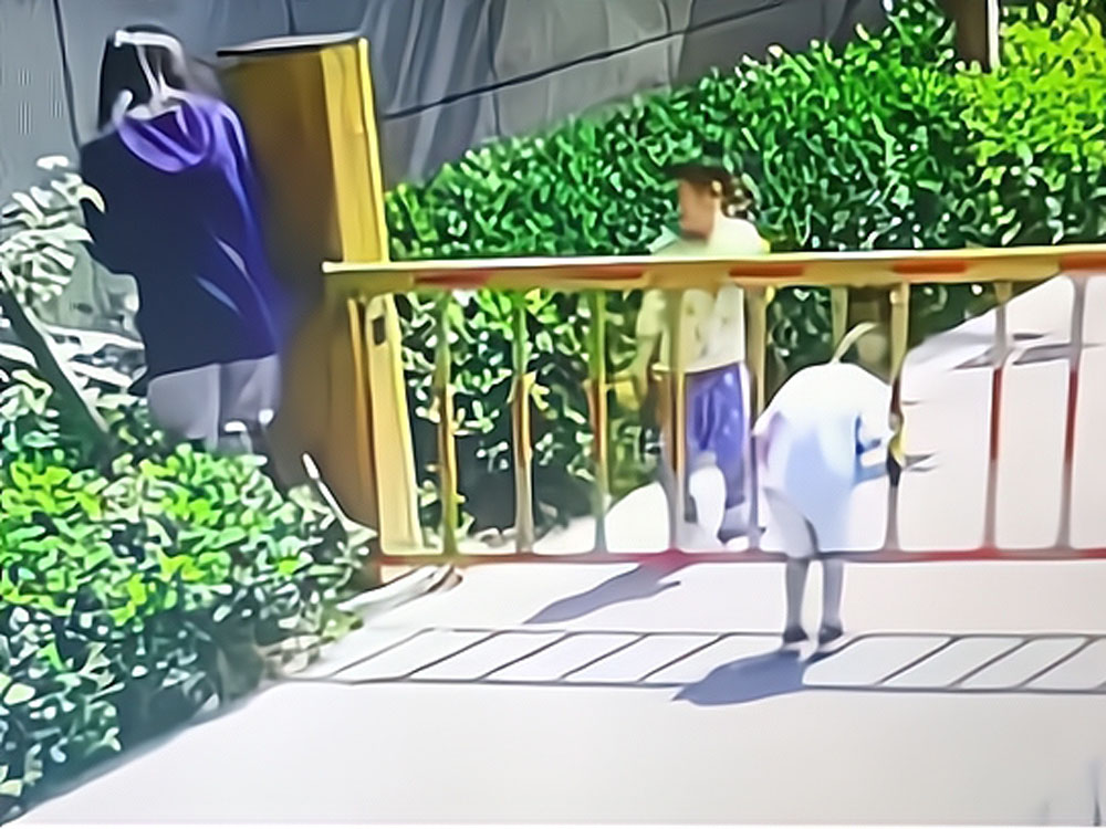第一名孩子鑽過了升降欄杆,第二名卻被卡住吊起來。
