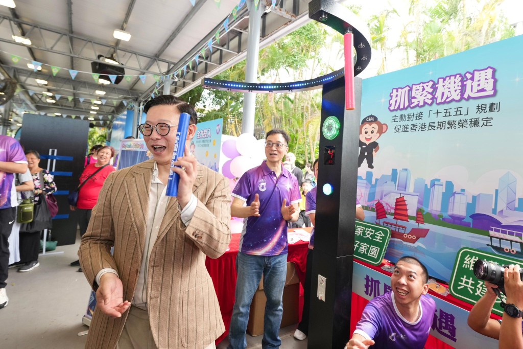 律政司副司長張國鈞（左）在懲教署署長黃國興（中）陪同下，參與以「十五五」規劃為主題的攤位遊戲。 