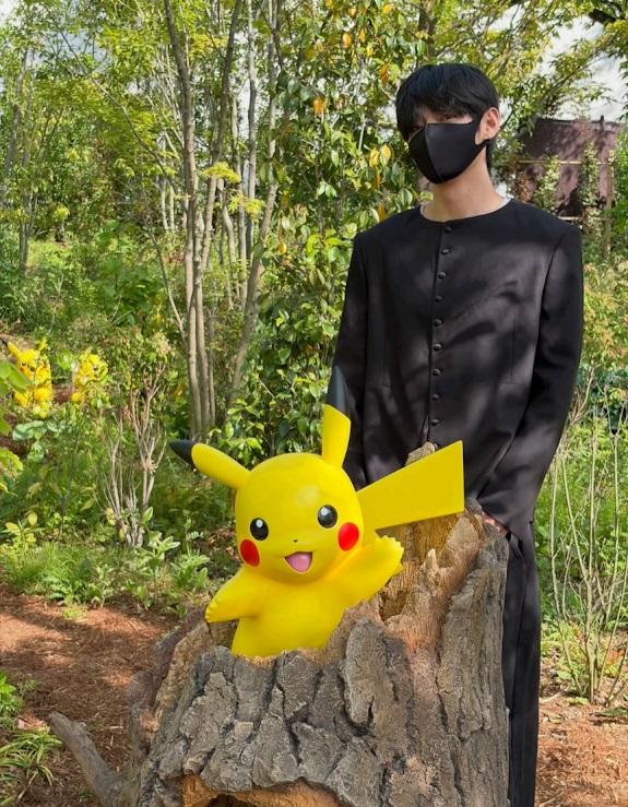 V戴上黑色口罩，站在比卡超旁邊打卡。