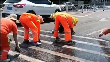 大連環衛工人在烈日下擦洗馬路斑馬線。