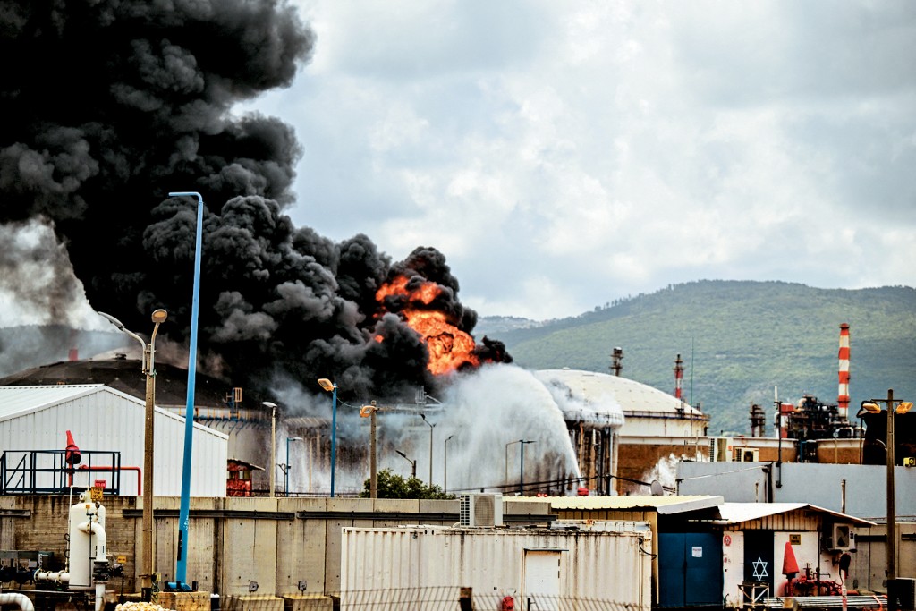 以色列海法一間煉油廠的設施被伊朗的導彈碎片擊中，冒起濃煙。 