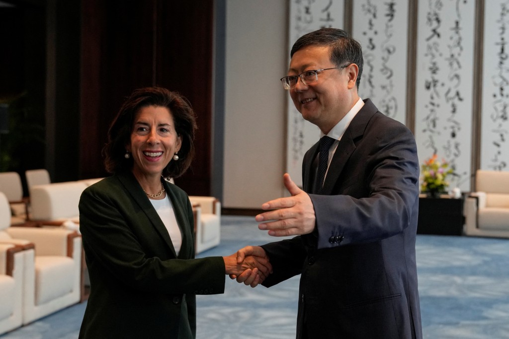 上​​海市委书记陈吉宁与美国商务部长雷蒙多握手。路透社