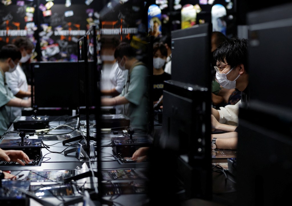 戴口罩的參觀者在東京電玩展展位上嘗試遊戲設備。路透社圖片