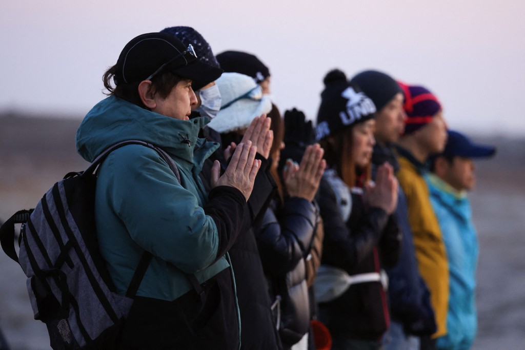 日本各地清晨有民眾在海邊為311大地震死難者祈禱。法新社