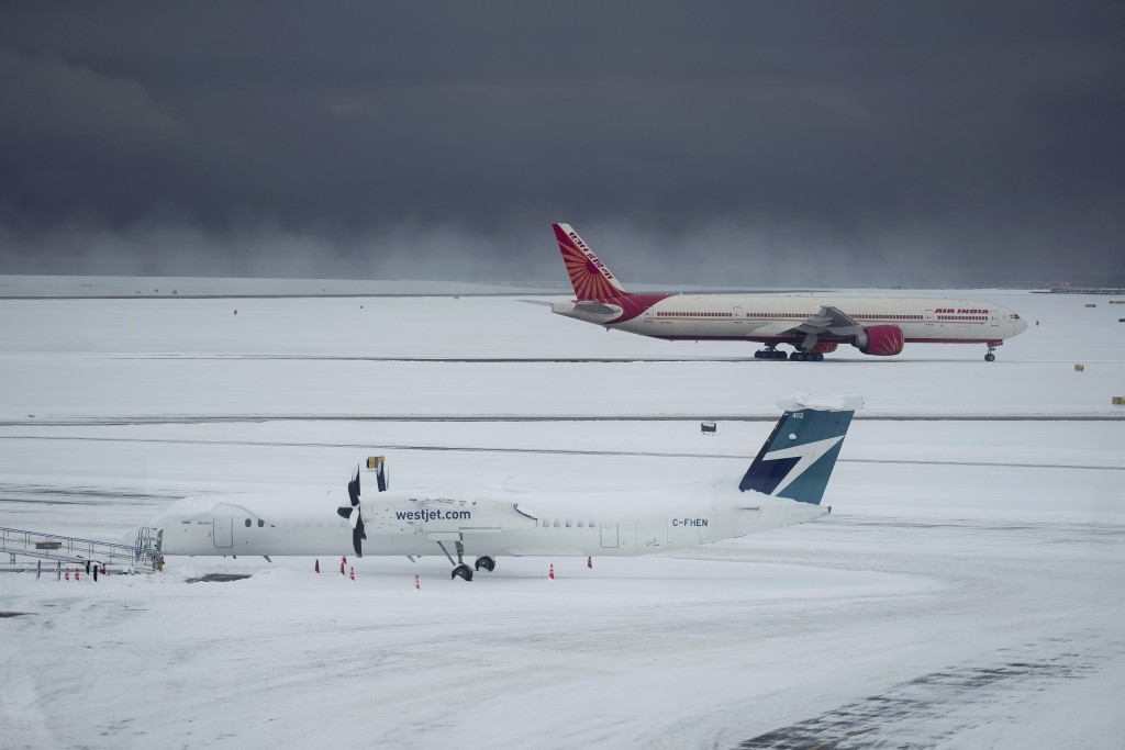 西捷航空和印度航空公司的飞机在暴风雪下停在温哥华国际机场。AP