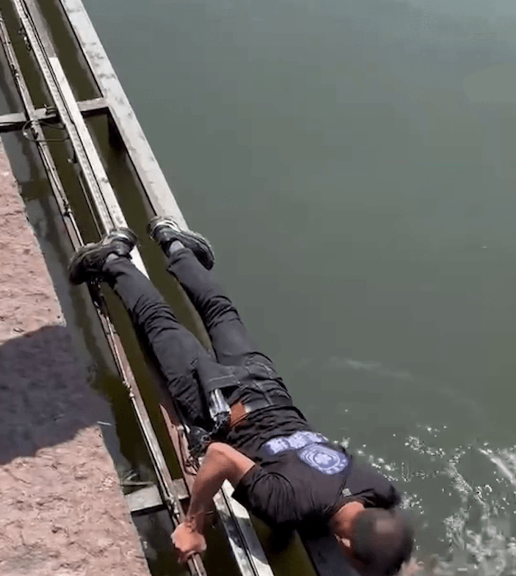 男子躺在湖边伸手捞手机。