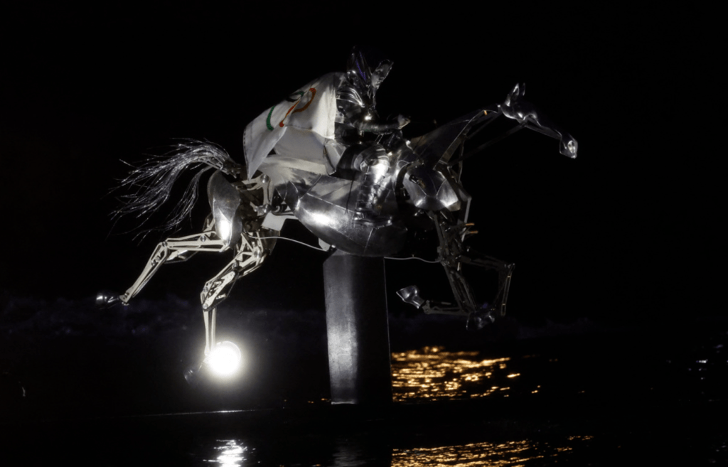 安排在漆黑的塞納河上凌空出現一隻機器馬，看上去就像聖經《啟示錄》中象徵死亡的天啟騎士。路透社