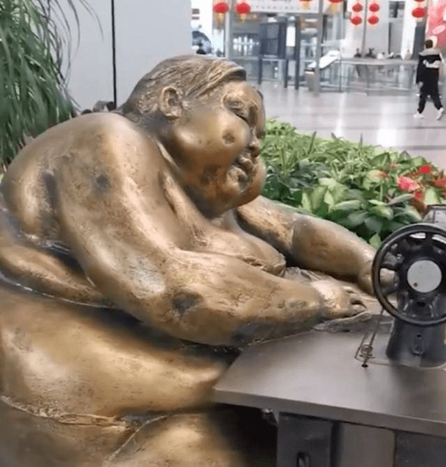 广州白云机场大厅摆放了一个「肥胖女人踩缝纫机」的雕塑。