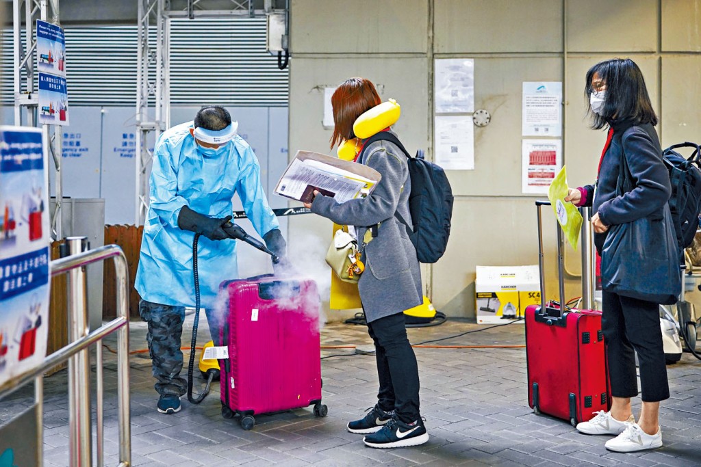 抵港者登車前,機場防疫人員消毒行李。