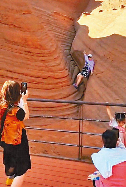 女子踩入陝西丹霞地貌拍照。