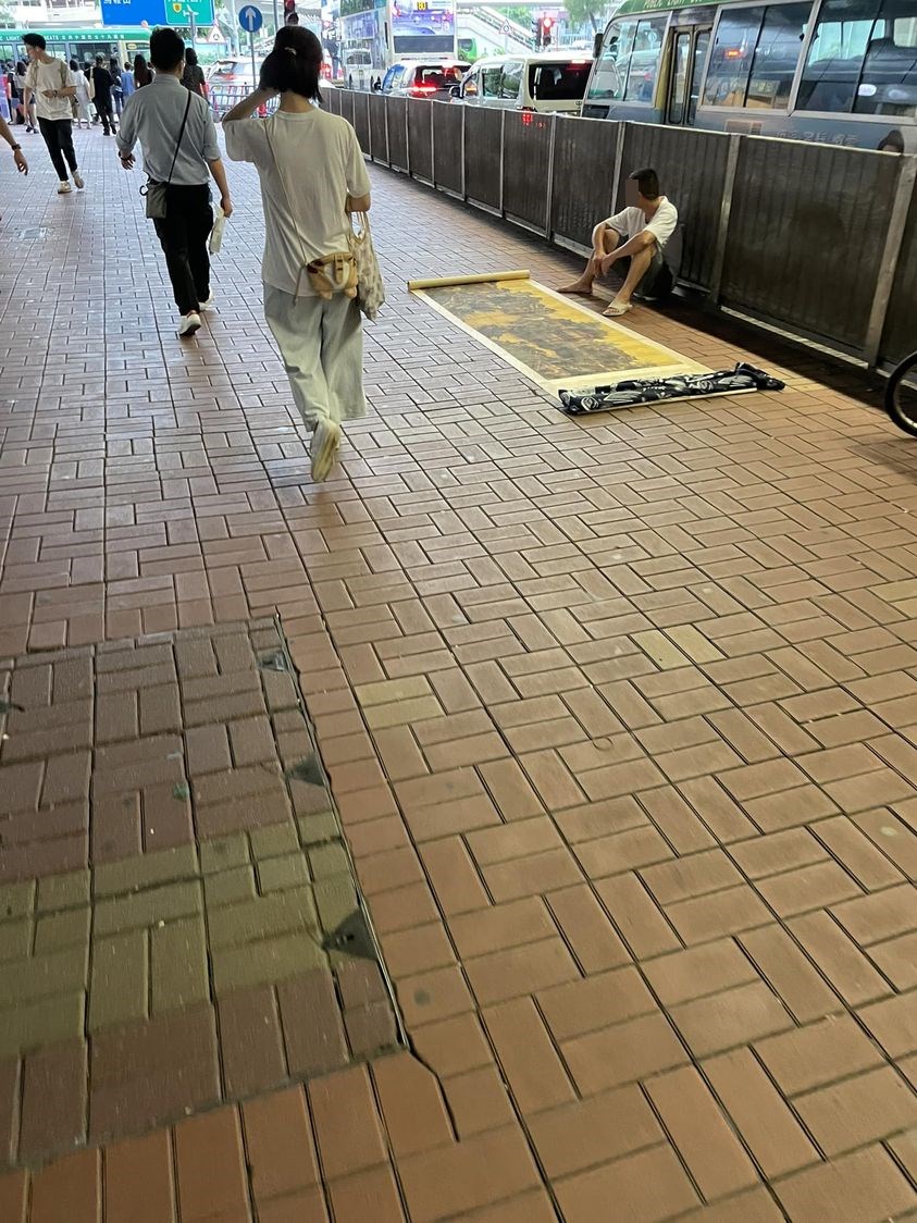 網民在大圍「野生捕獲」疑似名畫黨，該男子在人來人往的行人路上攤開畫作。