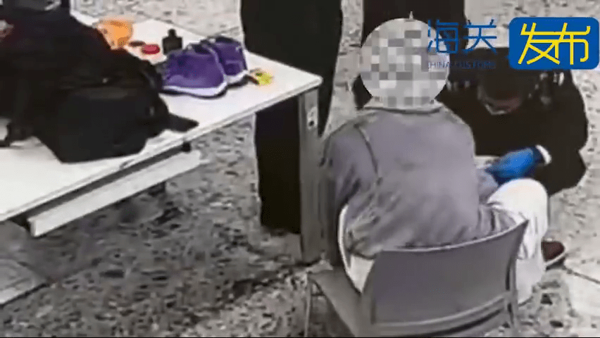 關員搜查男旅客的腳部。