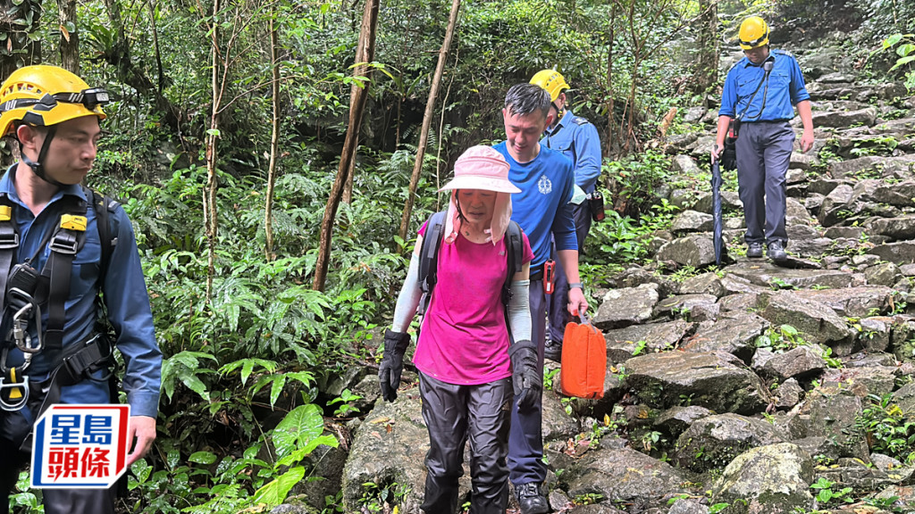 女事主由消防員及救護員陪同步行落山。