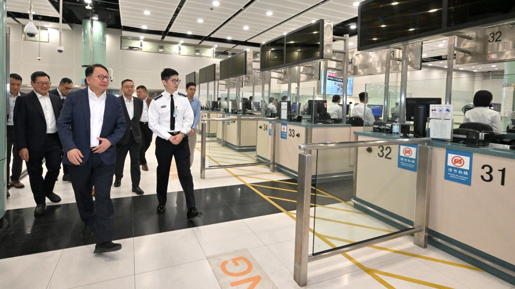陳國基（前排左）在郭俊峯（後排右三），視察落馬洲支線管制站，聽取入境事務處人員匯報。政府新聞處圖片