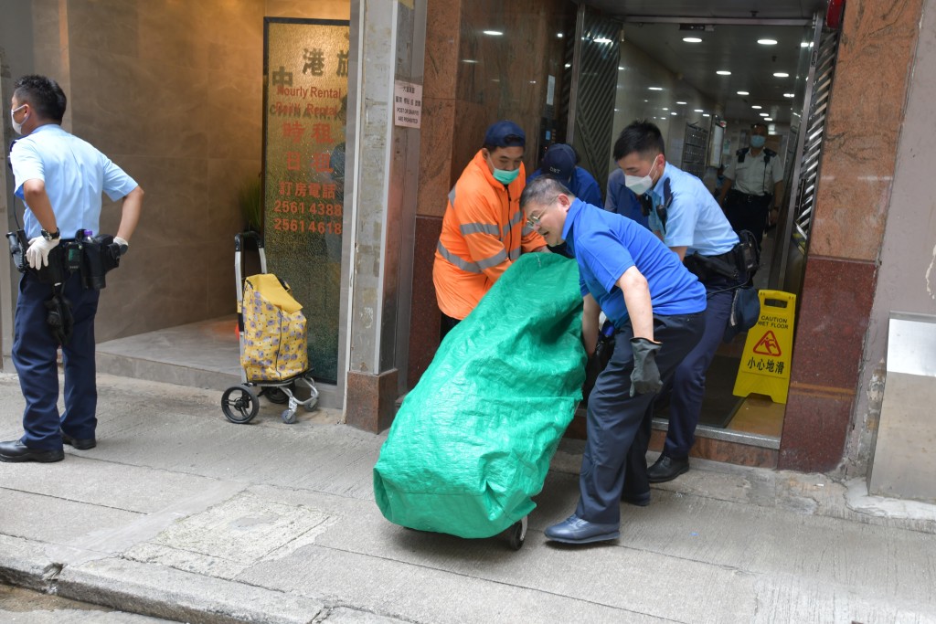 仵工與警員合力抬屍。 仵工與警員合力抬屍。