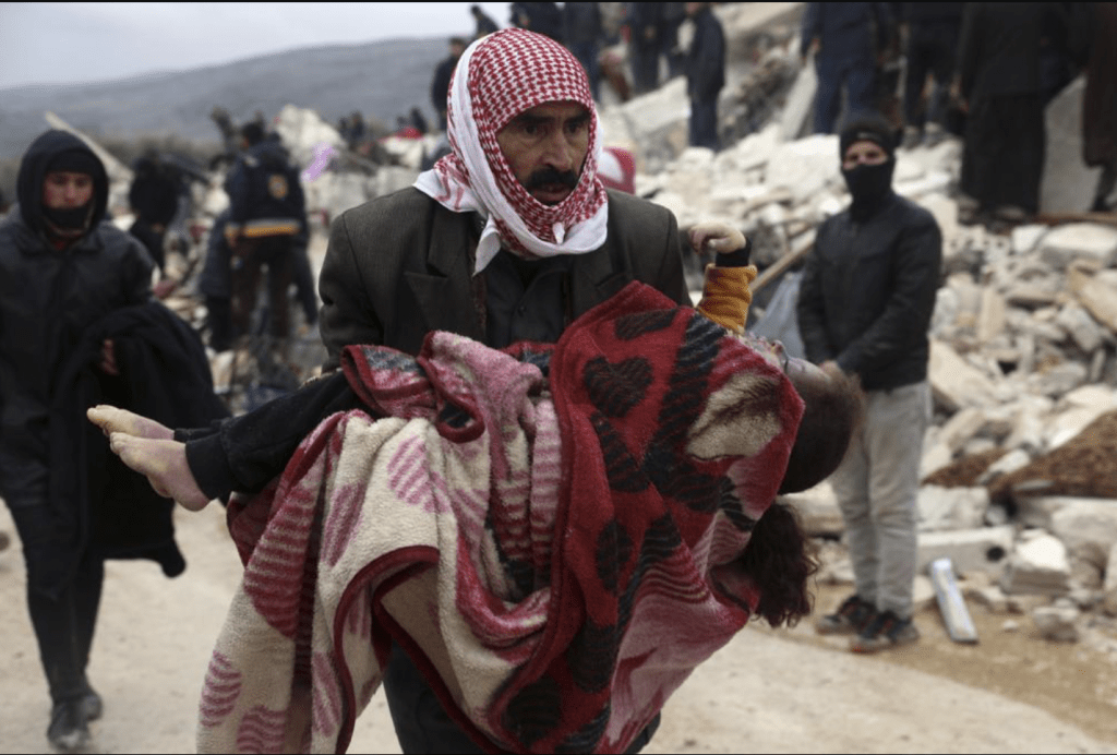 一名男子在叙利亚伊德利卜省土耳其边境附近的贝斯尼亚村抬著一名地震遇难者的尸体。AP