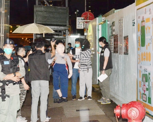 警方押解其中一名疑犯到涉事地點重組案情。