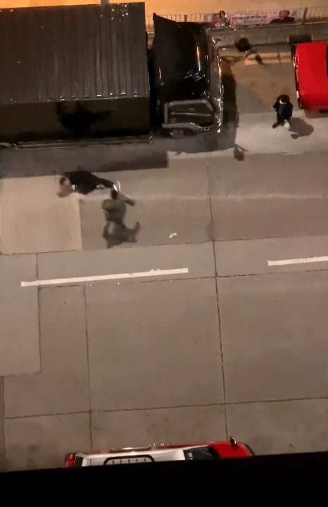 黑衣男倒在一架货车旁。