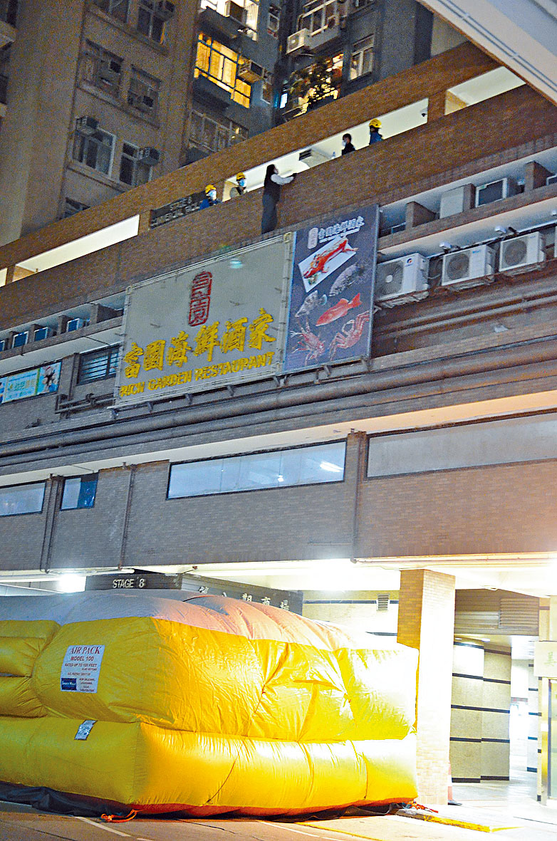 女保安危站商场三楼石壆，消防张开救生气垫戒备。