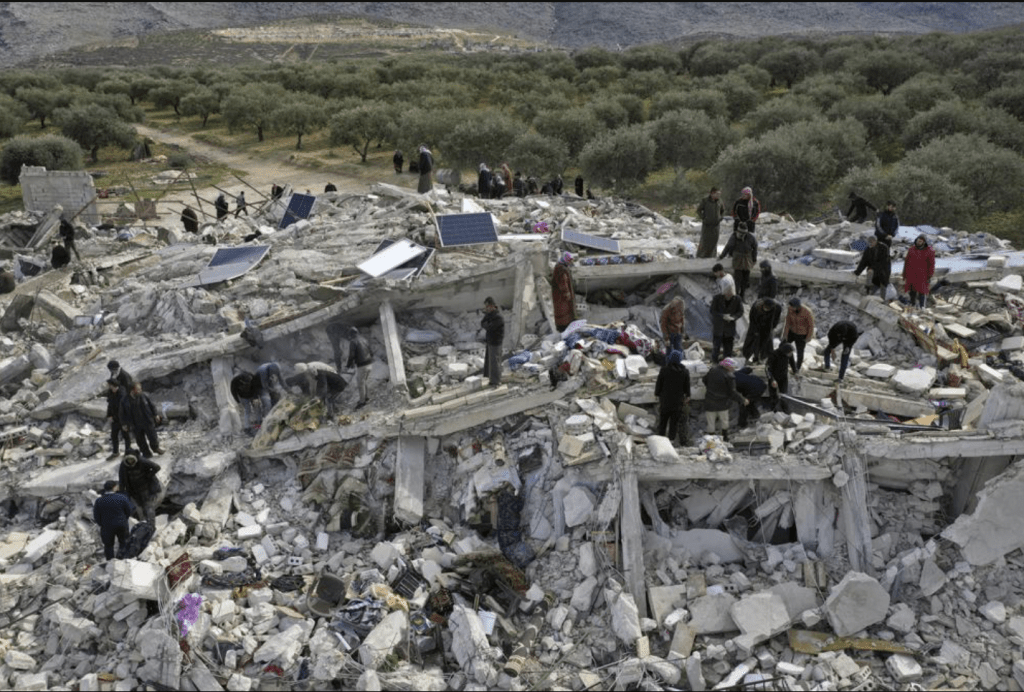 民防工作者和居民在敘利亞伊德利卜省土耳其邊境附近的后宮鎮倒塌建築物的廢墟中搜尋傷者。AP