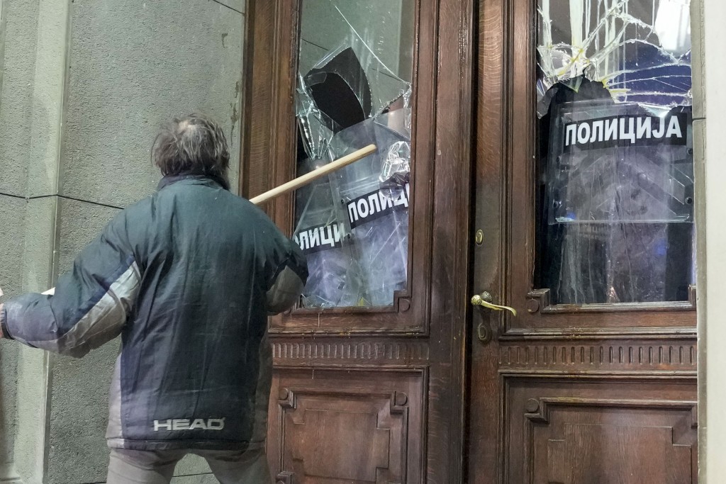 示威者用旗桿打破市政府大樓的窗戶。美聯社