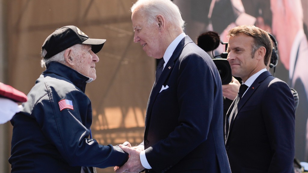 拜登（中）與馬克龍（右）問候仍然在世的二戰老兵。 美聯社