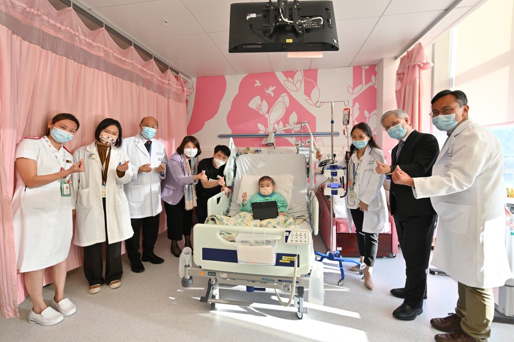 李夏茵（左四）和香港兒童醫院行政總監李子良醫生（右二）探望住院男童致遠。(政府新聞處圖片) 