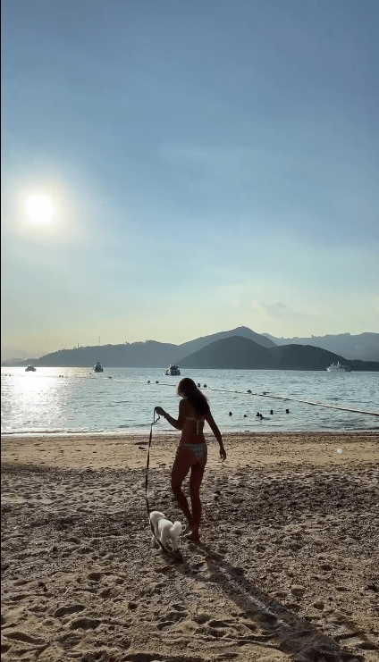 何珮瑜在夕陽餘暉下漫步沙灘，唯美牽狗背影顯得身材比例極佳。