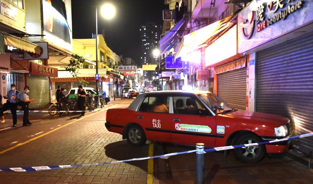 的士撞及店鋪鐵閘,警方封鎖現場調查。尹敬堂攝