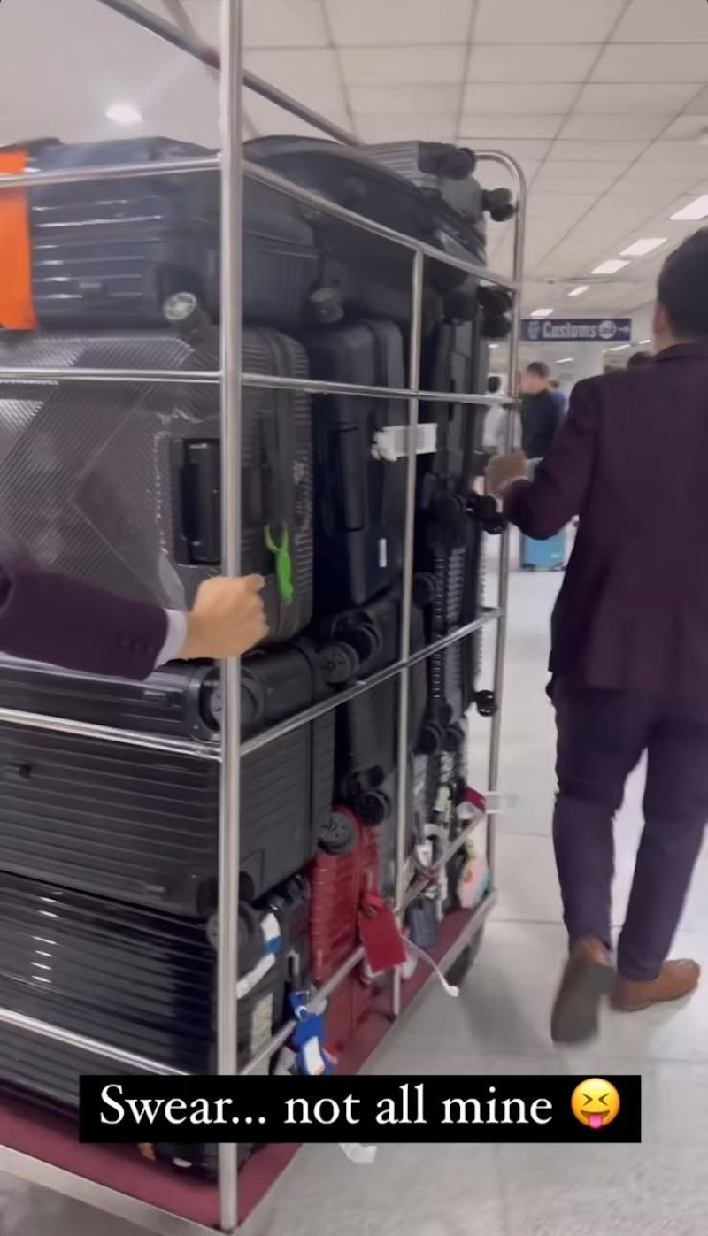 两位工作人员为他们推行李，目测他们带了13个行李喼出游，行李多到堆满手推车。