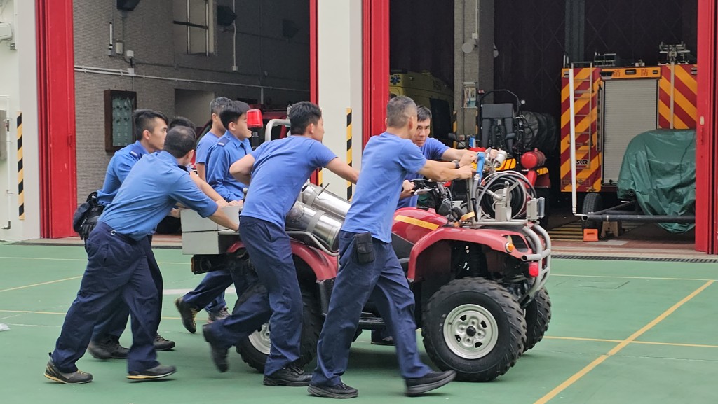 多名消防员将迷你抢救车推回消防局内。