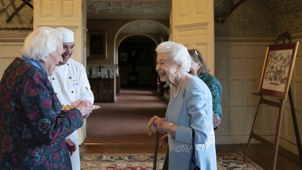 2022年登基白金禧，伊利沙伯二世在桑德靈厄姆宮以「加冕雞」杯形酥皮餡餅宴客，左一是當年有份協助製作「加冕雞」的伍德女士（Angela Wood）。 美聯社