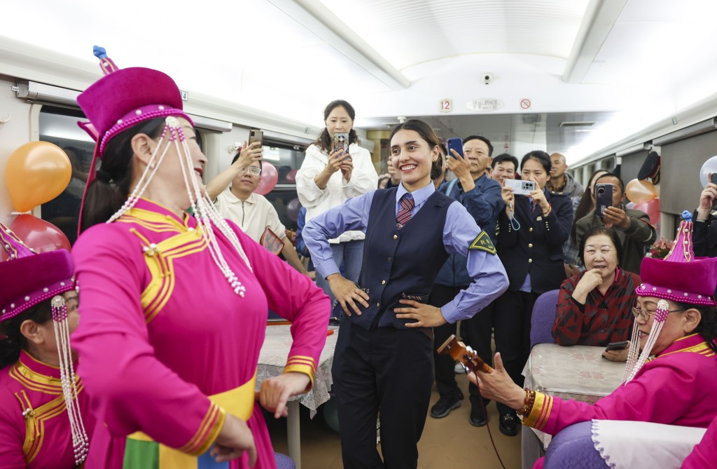 在由喀什开往成都西的列车上，艾尔开牙·多力开与民间艺人一起为乘客跳舞。 新华社