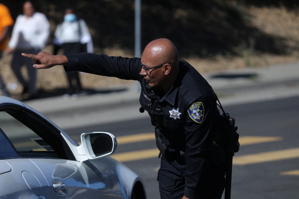 美國加州奧克蘭一所學校附近發生槍擊事件後，一名警察在封閉的道路上指揮交通。路透