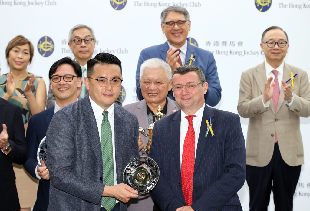 马会董事韦安祖 (右) 将精英杯及银碟颁予「绿族无限」的练马师伍鹏志 (左)。