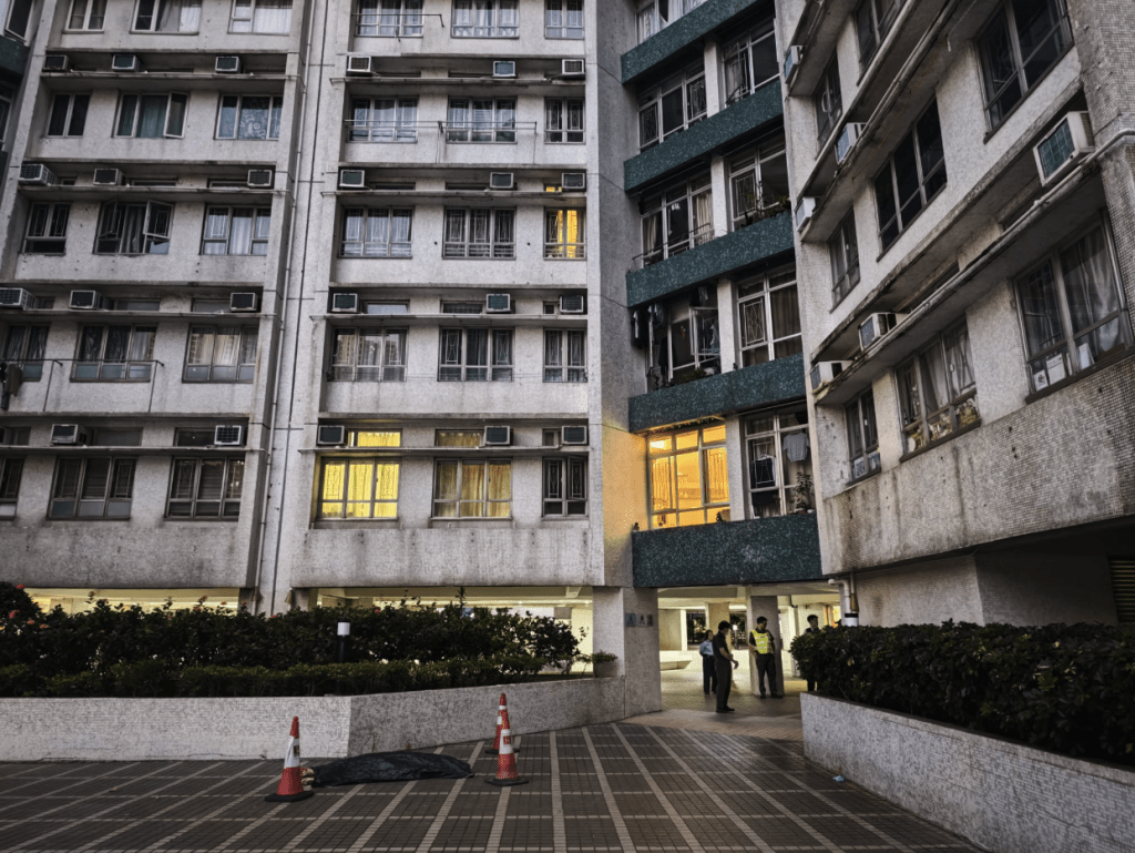 警方用綠色布將遺體掩蓋，並在現場調查男子墮樓原因及經過。黎志偉攝