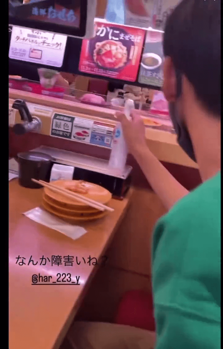少年拿起酒精喷樽，对著旋转寿司转盘。