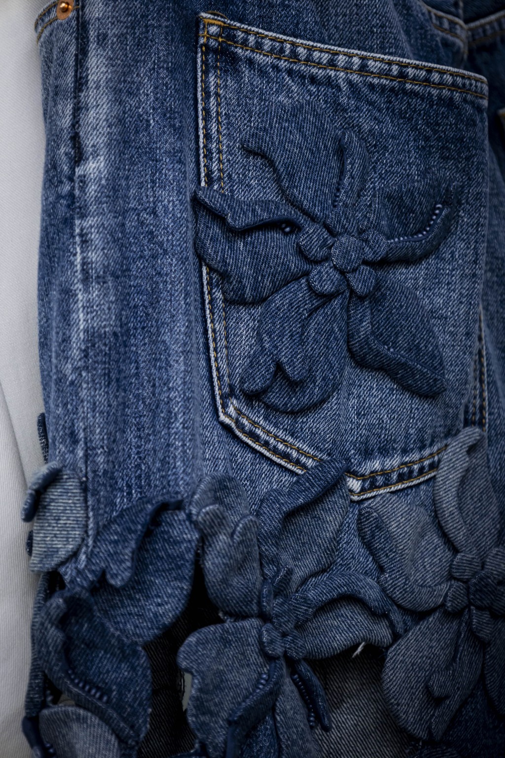 牛仔裤的口袋缀以立体花卉刺绣。（Valentino）