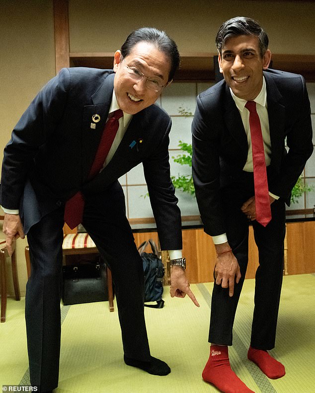 辛伟诚（右）和岸田文雄向传媒展示印了「广岛东洋鲤鱼」（Hiroshima Toyo Carp）棒球队标志的红袜。路透社