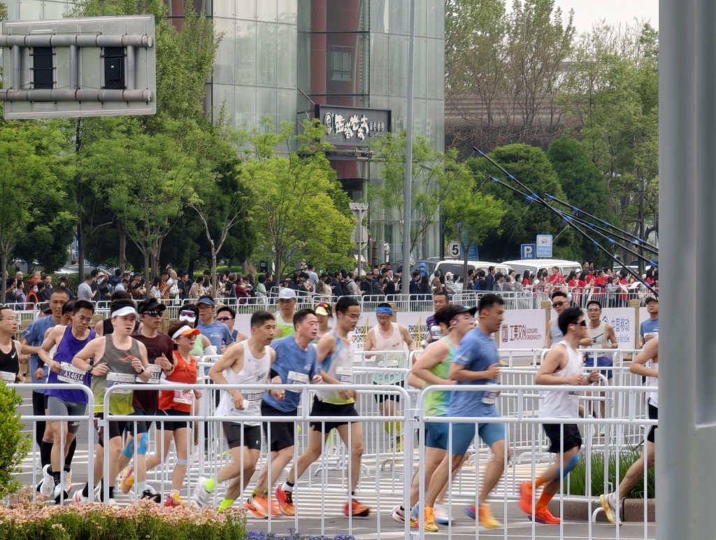 北京人形机械人半马19日早上开跑，大批市民围观。杨浚源摄